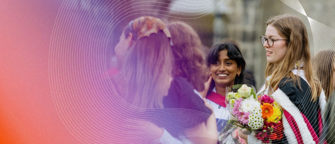 Female students are gathered, smiling and celebrating, in graduation robes.